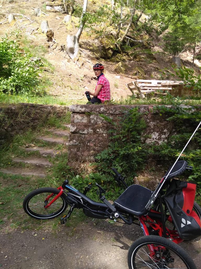 Christiane sitzt auf Felsen. Vor ihr ihr Trike